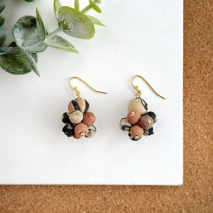 Kantha desertscape drop earrings on white corkboard background.