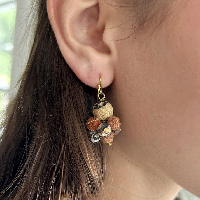Close-up of a person wearing a kantha desertscape earring with a blurred background