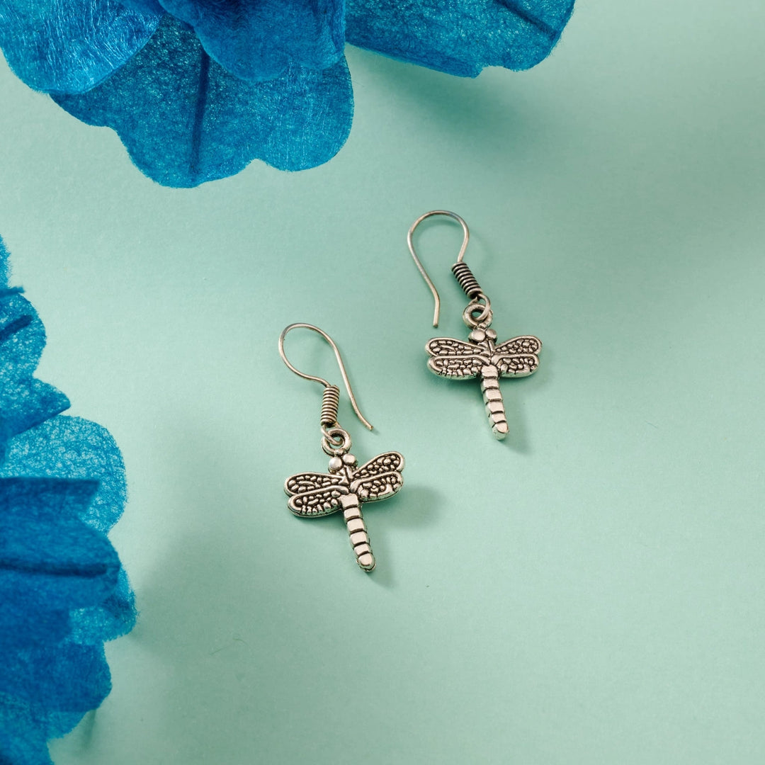 Dragonfly-shaped earrings on a light blue background with blue flowers.