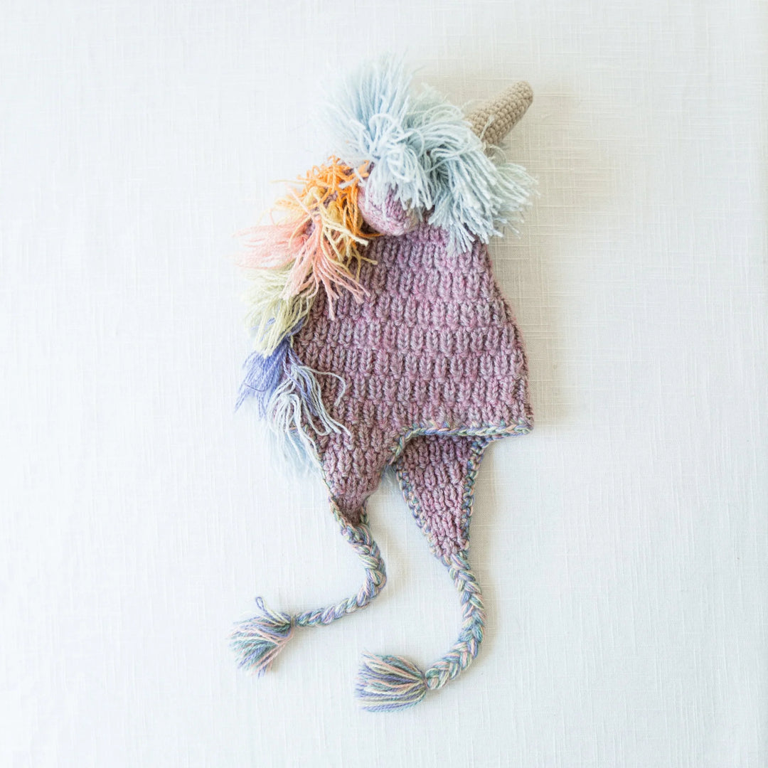 a kids pastel unicorn animal hat on a cream background