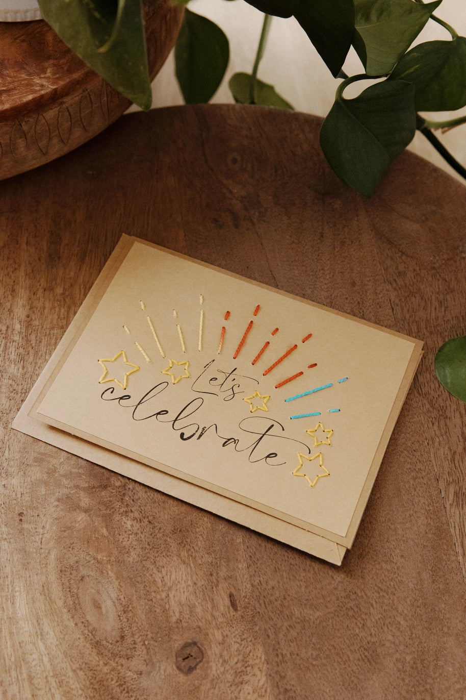 Greeting card with 'Let's celebrate' text on a wooden surface.