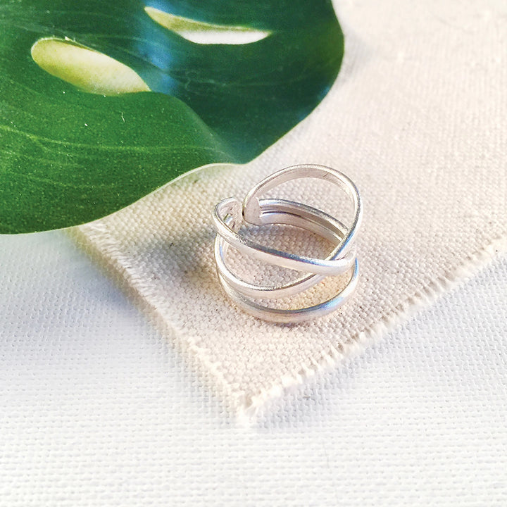 Silver ring on a white fabric background with a green leaf.