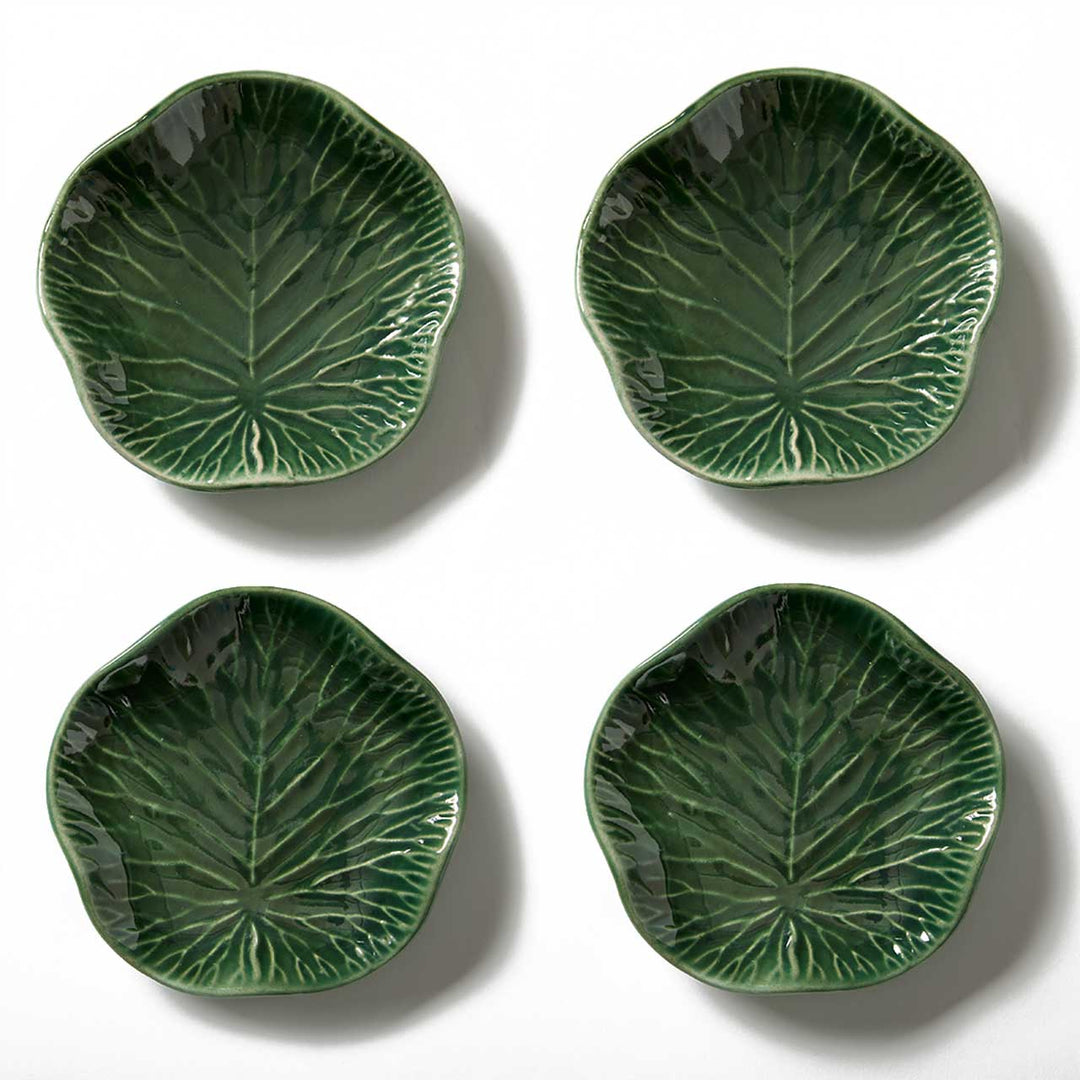 Four green ceramic leaf-patterned plates on a white background