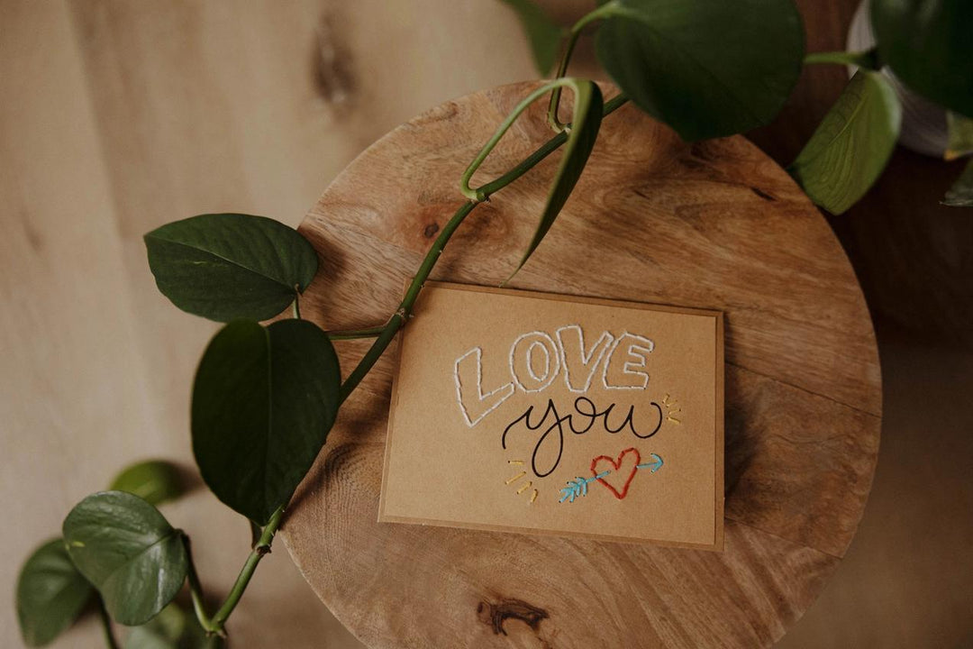Card with 'Love you' text on a wooden surface with leaves