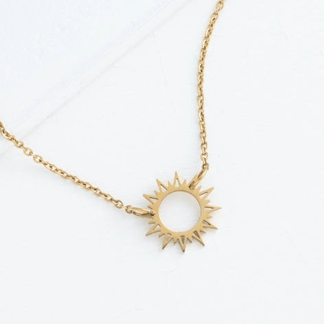 Gold sun-shaped pendant necklace on a white background