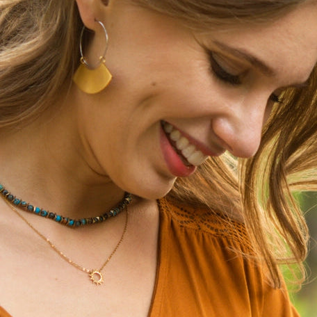 Woman wearing a necklace and earrings with a blurred natural background