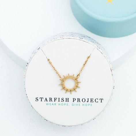Gold necklace on a Starfish Project card with a blue box in the background