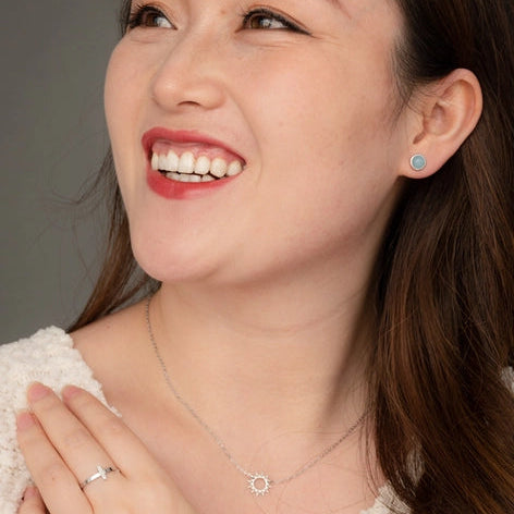 Woman wearing a necklace and earrings with a neutral background