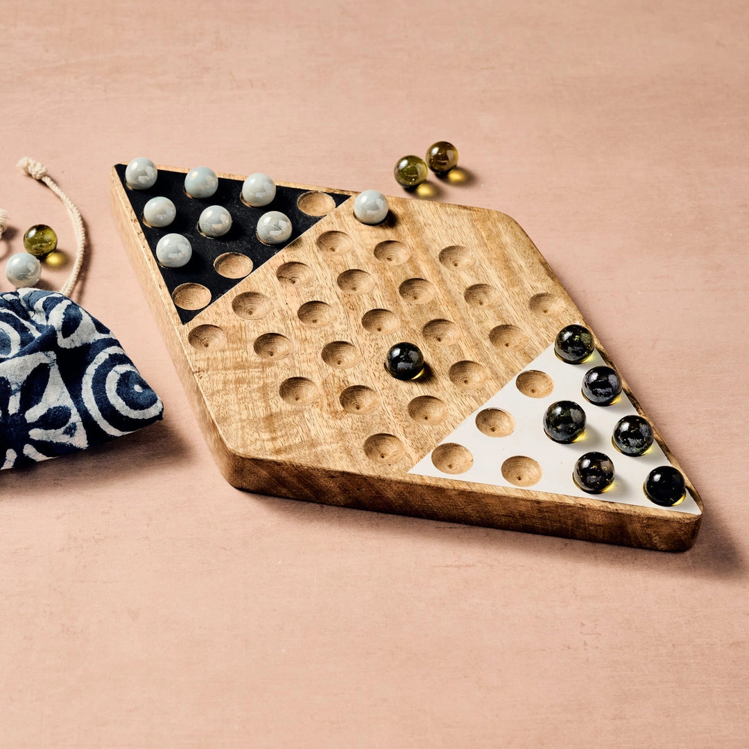 Wooden Chinese Checkers game board with marbles on a beige background
