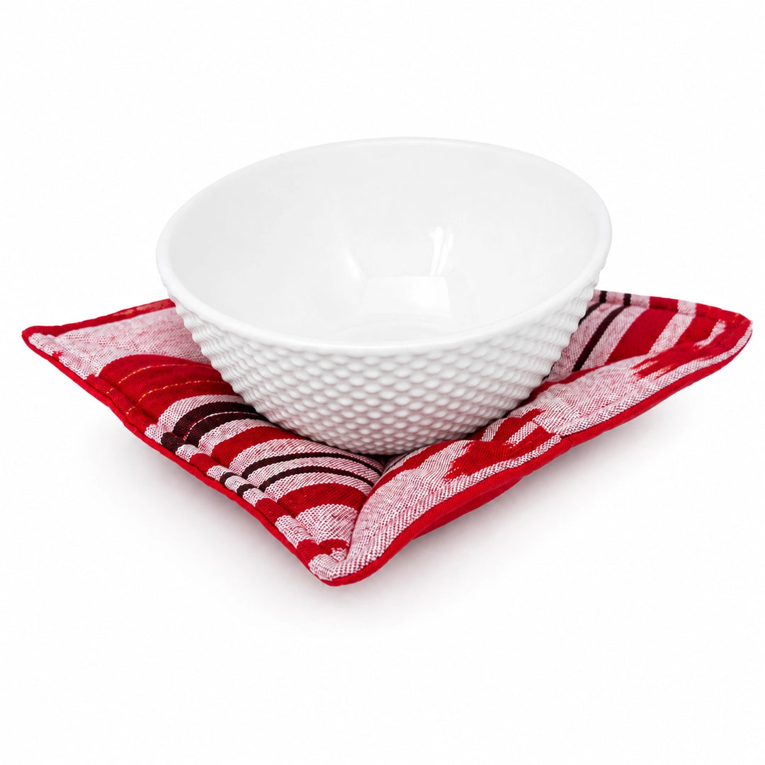 A white textured ceramic bowl resting on a red and white patterned bowl cozy, photographed on a clean white background.