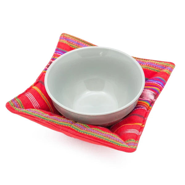 White bowl on a colorful red and multicolored bowl cozy