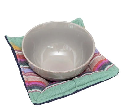 White bowl on a colorful fabric bowl cozy with a white background