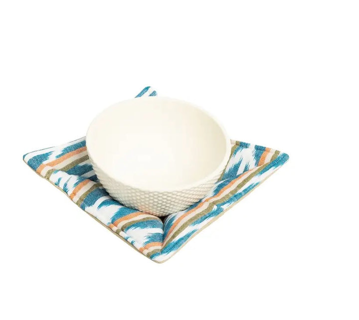 White bowl on a colorful woven bowl cozy with a white background