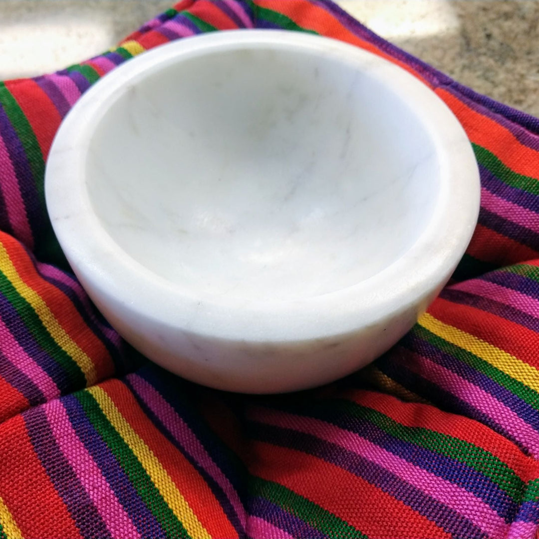 White ceramic bowl on a colorful striped fabric bowl cozy  background