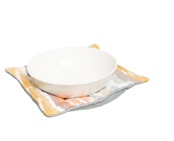 White bowl on a striped fabric bowl cozy with a white background