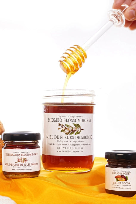 big jar of miombo blossom honey with glass honey dipper and mini jars of honey