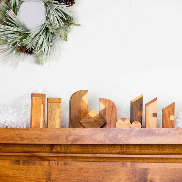 Wooden nativity on a mantelpiece with a Christmas wreath in the background