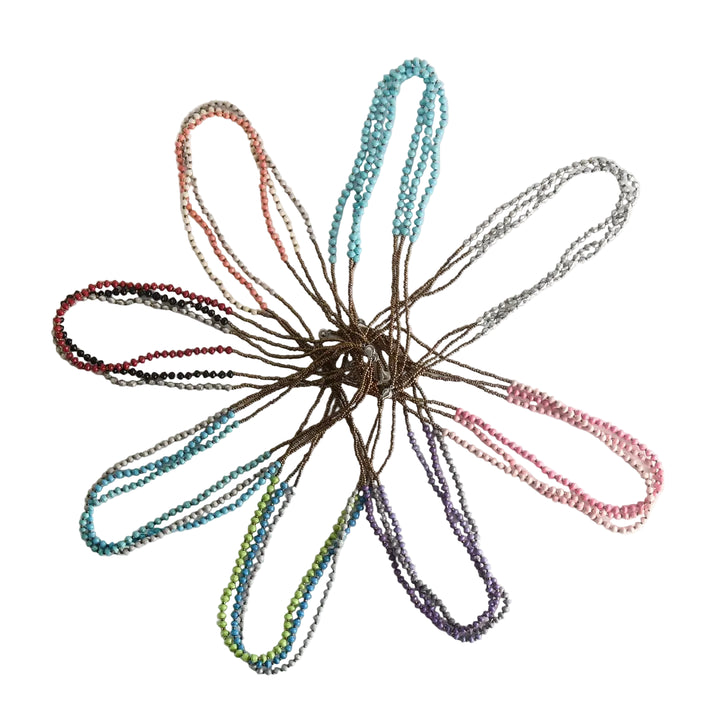 Colorful paper bead necklaces arranged in a circular pattern on a light background