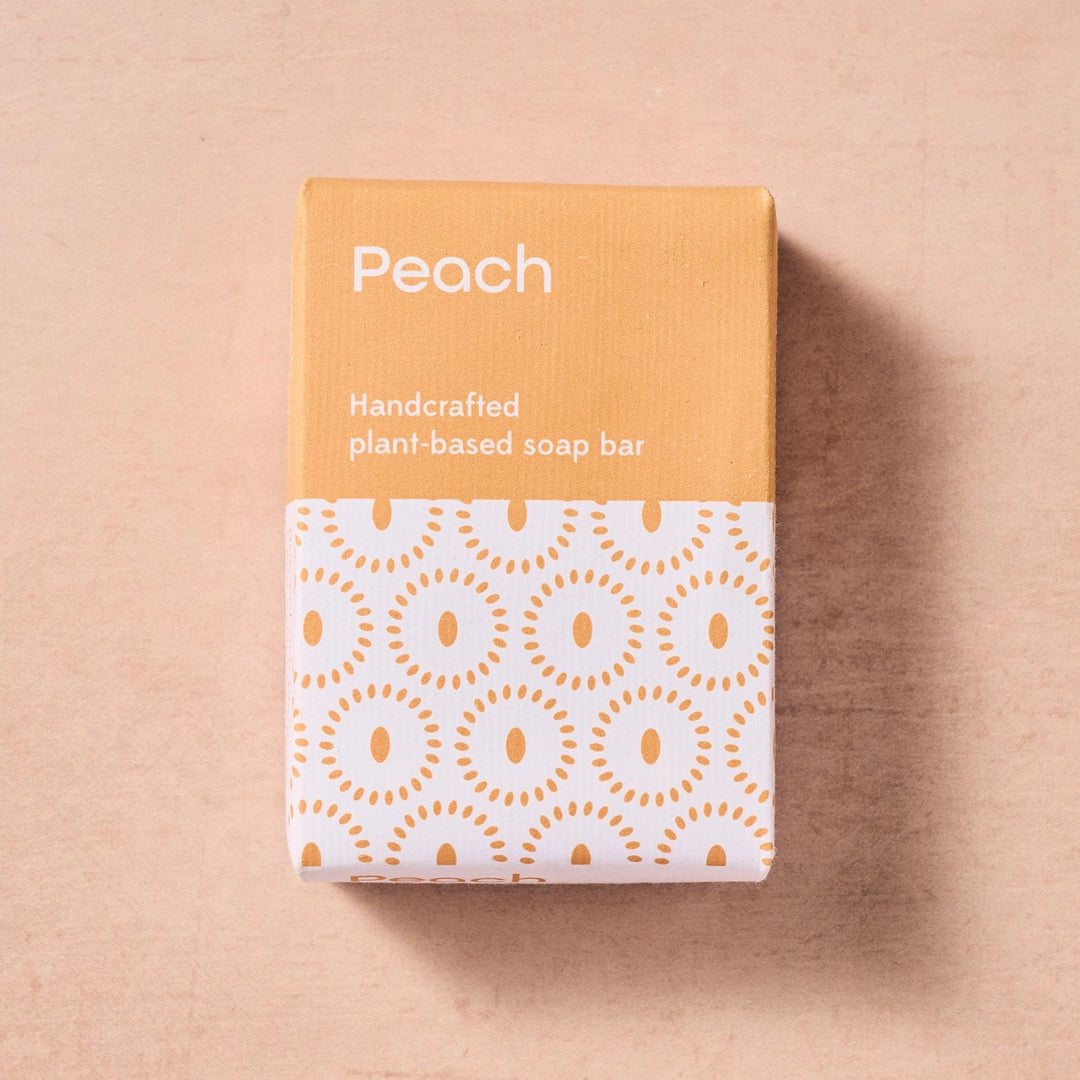 Handcrafted plant-based soap bar packaging with peach color on a beige background