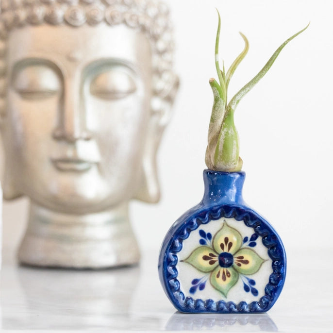 Decorative ceramic vase with floral design in front of a Buddha statue.