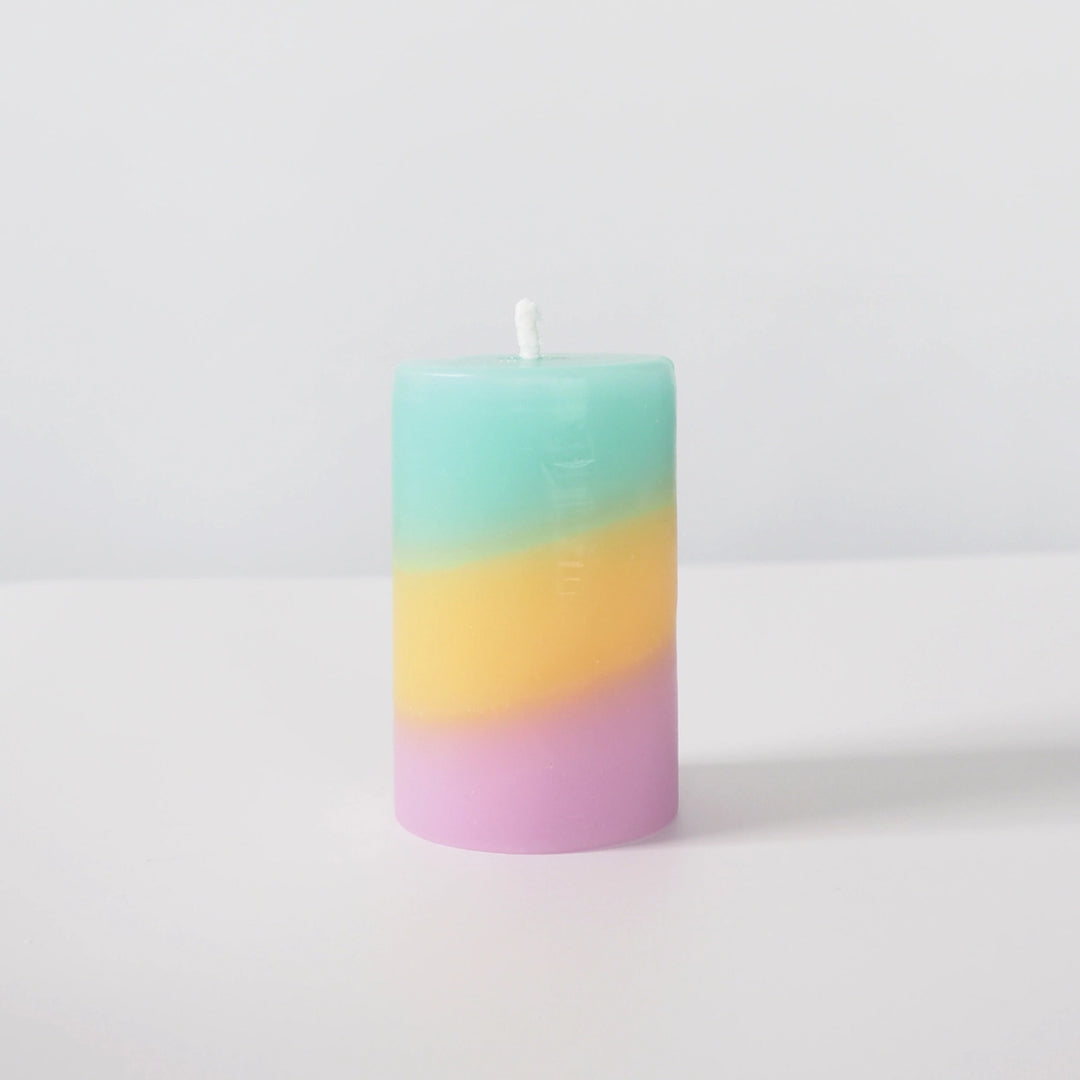 Gradient candle from green to pink on a white background