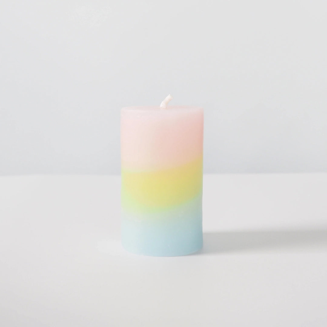 Pastel gradient candle on a light gray background