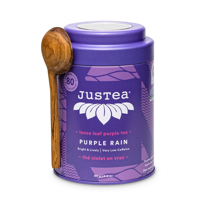 JusTea Purple Rain loose leaf purple tea canister with a wooden spoon on a white background