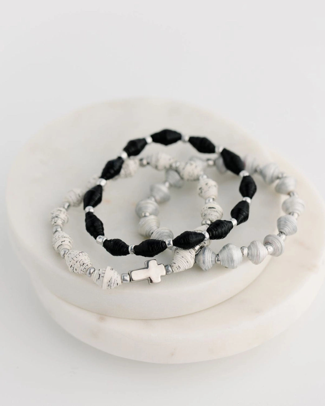 Set of black and white beaded silver-plated bracelets on a white surface