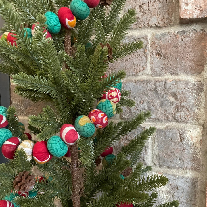 red and green saree garland on a christmas tree with brick background