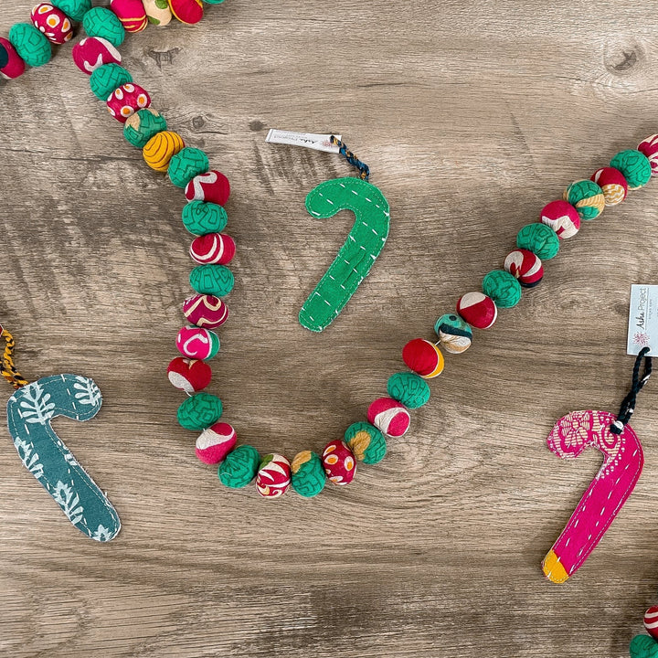 red and green saree garland laid across wooden background with candy canes