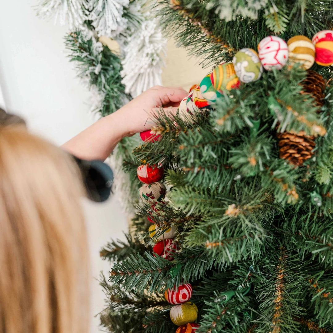red and green saree garland being hung on christmas tree