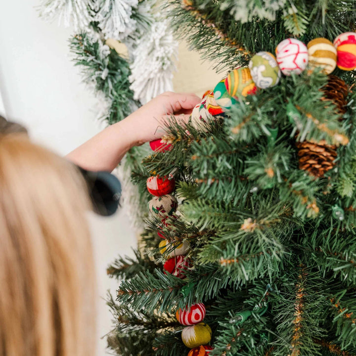 red and green saree garland being hung on christmas tree
