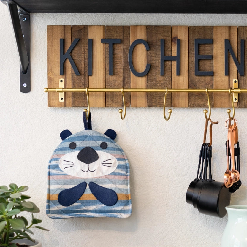 Wooden sign with 'KITCHEN' on a wall-mounted hook rack with kitchen items.