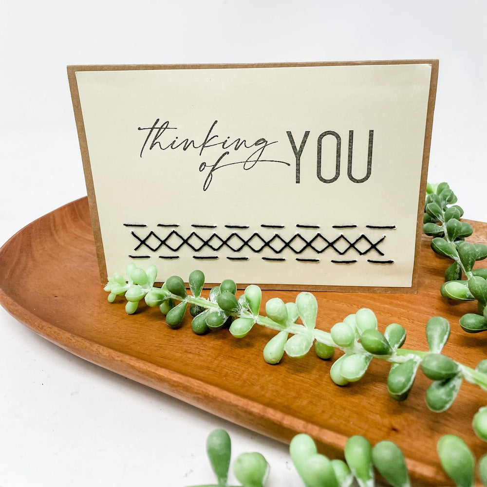 Card with 'thinking of YOU' text on a wooden stand with succulents