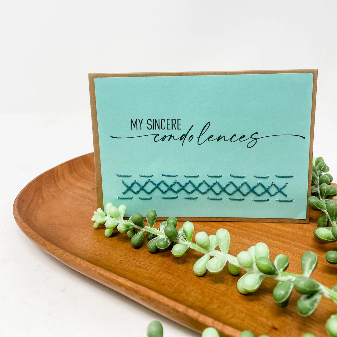Card with 'My sincere condolences' text on a wooden tray with succulents