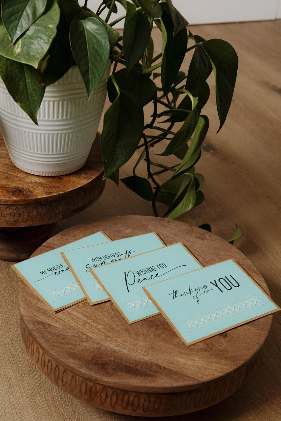 Four light blue cards with text on a wooden surface with a plant in the background