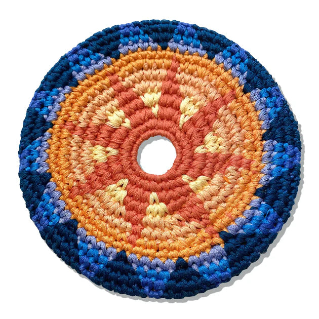 Round crocheted flying disk with concentric color rings on a white background