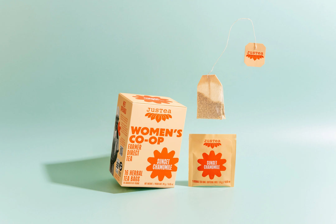 Justea Women's Co-op tea packaging on a light blue background
