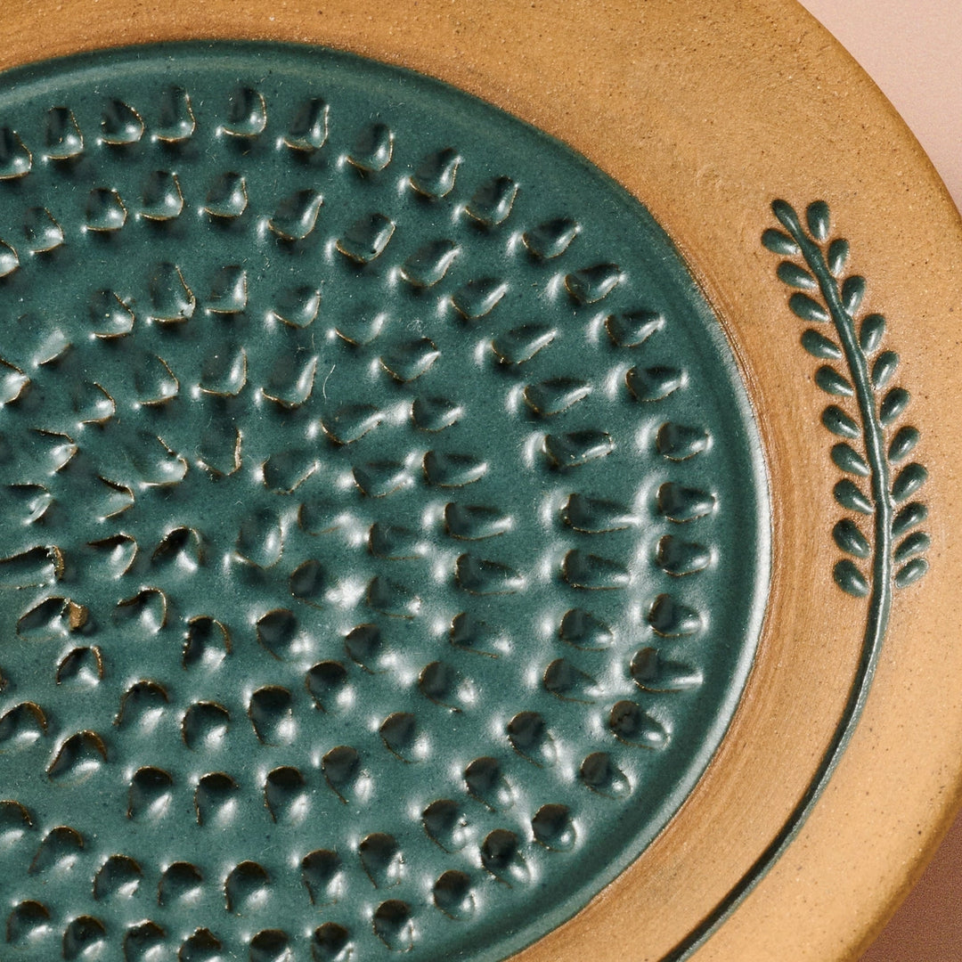 Close-up of a textured ceramic grater with a wheat design