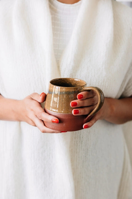 Person holding a ceramic mug with a plain white background