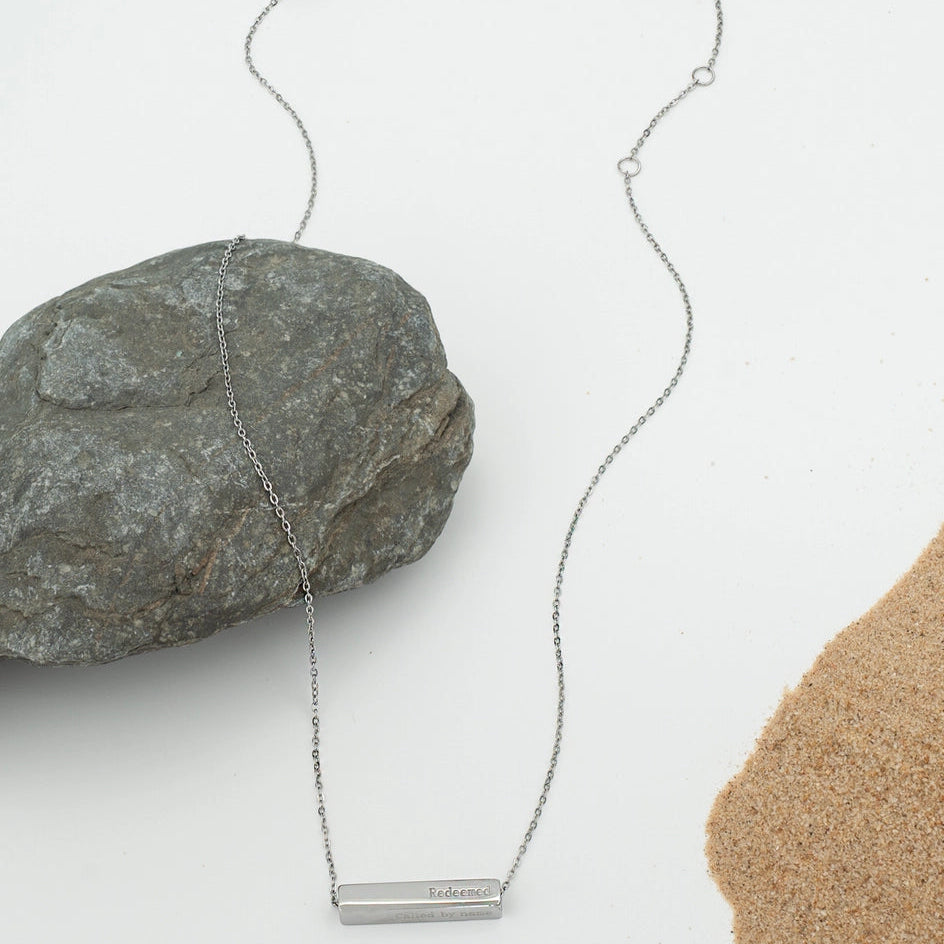 Silver necklace with a bar pendant on a white background