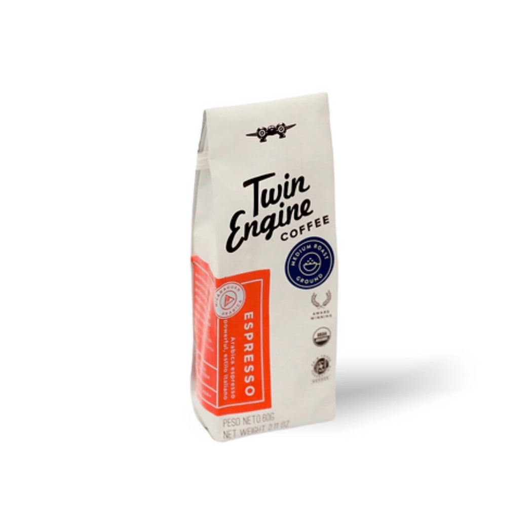 A 112g bag of Twin Engine Coffee Espresso on a white background, featuring a white bag with a prominent orange-red label and black text.