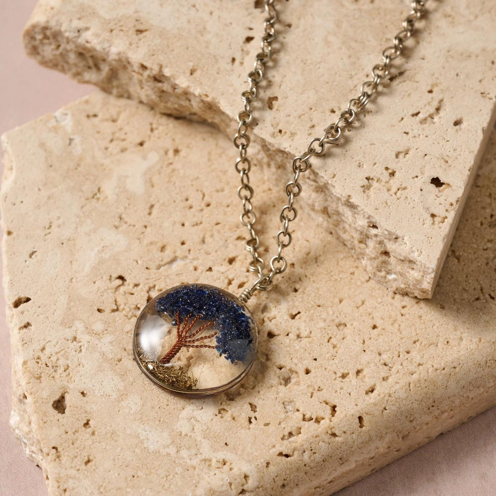 Tree of Life Necklace with a round pendant featuring a tree design on a stone surface