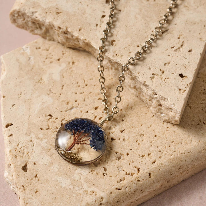Tree of Life Necklace with a round pendant featuring a tree design on a stone surface