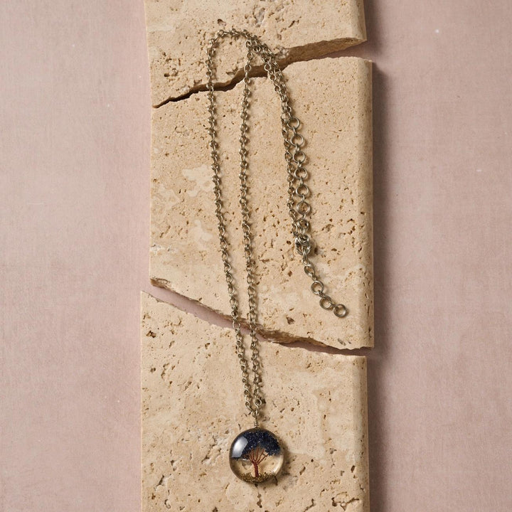 Tree of Life necklace with a pendant on a textured stone surface