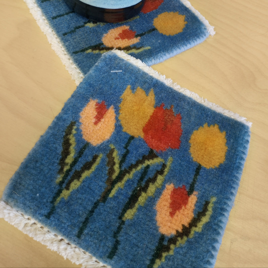 Two tulip coasters with a mug on a wooden surface