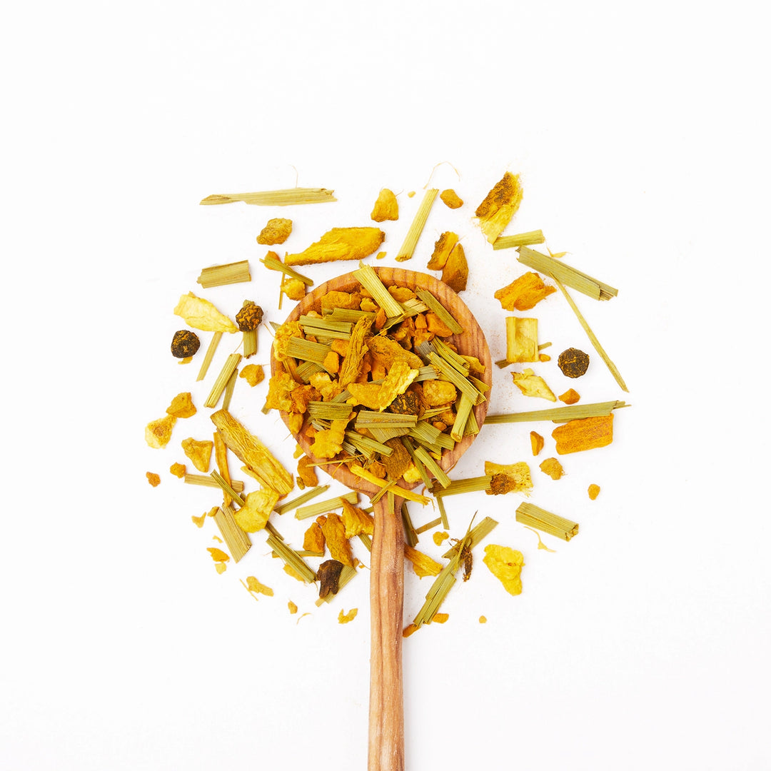 Wooden spoon filled with dried turmeric and ginger on a white background