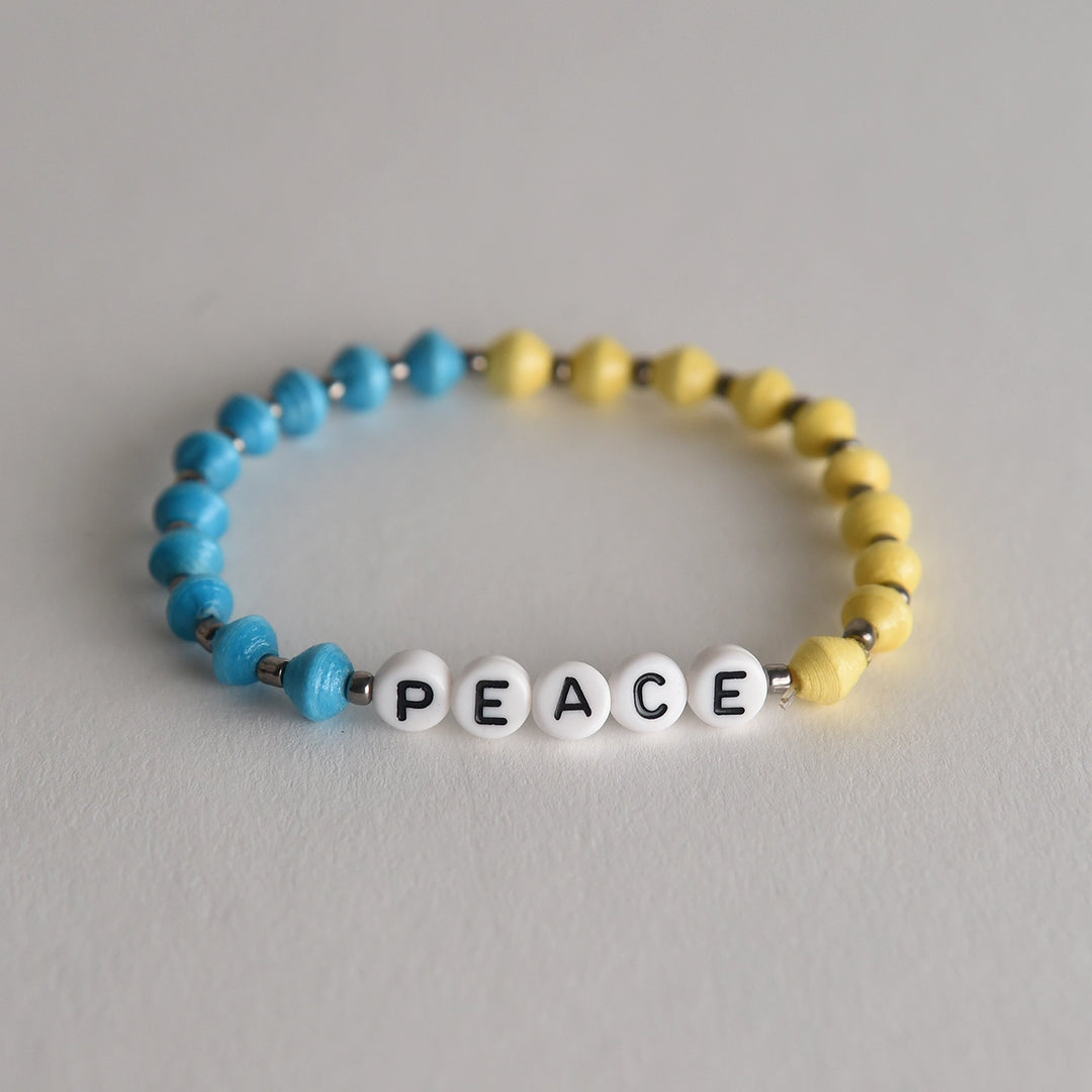 Beaded bracelet with 'PEACE' beads on a gray background