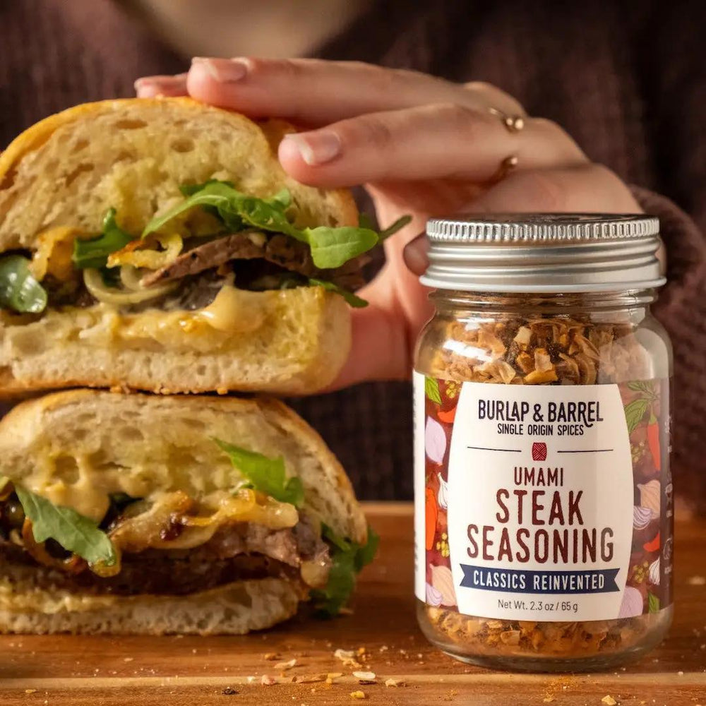 Burlap & Barrel Umami Steak Seasoning jar with a sandwich in the background