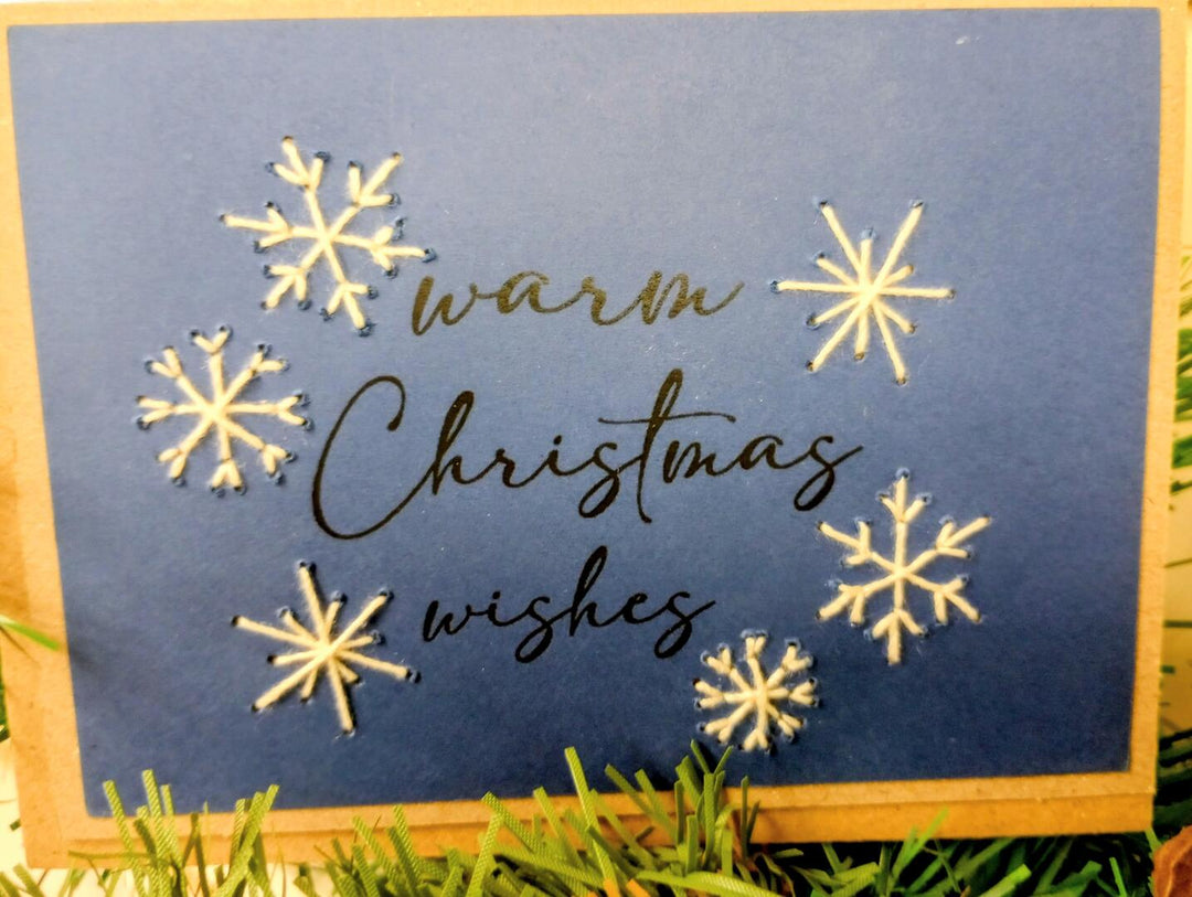 Card with 'warm Christmas wishes' text and snowflake designs on a blue background